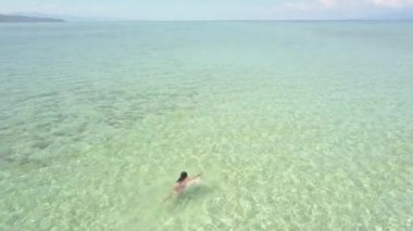 Philipines'te berrak bir okyanusta yüzen bir turistin havadan görünümü.