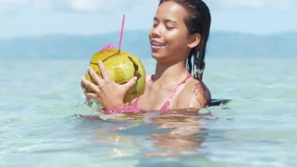 Крупним планом знімок щасливої жінки, що п'є кокос у спокійній відпустці на острові — стокове відео