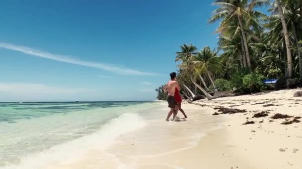Šťastný mladý pár na pláži, drží se za ruce a točí se kolem sebe — Stock video