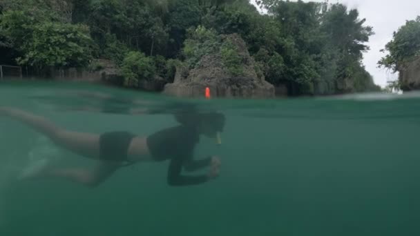 Foto sobre el agua, vista lateral de una mujer buceando en agua turquesa . — Vídeo de stock