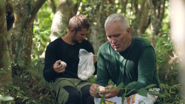 Dois montanhistas comendo ovos cozidos na selva . — Vídeo de Stock