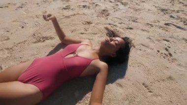 Genç esmer kadın plajda güneşlenme sahiptir.