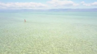 Kadın onu tatil banyo sahiptir ve adada okyanusta sıçrayan, havadan görünümü.