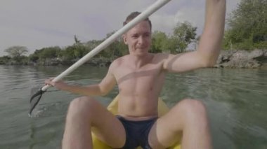 Tropik okyanusta kano süren mutlu bir adam.