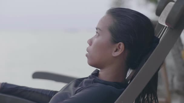 Portrait of a young carefree woman sitting on a chair in the beach. — Stock Video