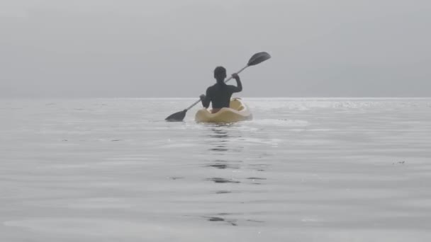 Kobieta wiosłująca na środku spokojnego otwartego oceanu. Widok z tyłu. — Wideo stockowe