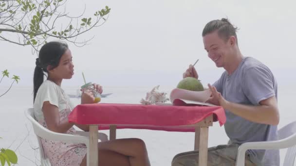 Couple amoureux souriant et lire l'histoire dans le livre tout en buvant du jus frais . — Video