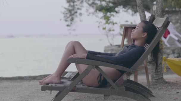 Jonge vrouw zit op strandstoelen ontspannen in het rustige strandresort. — Stockvideo