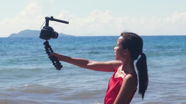 DSLR 카메라를 들고 삼각대로 촬영 한 젊은 여성 블로거의 사진. — 비디오