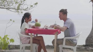 Mutlu genç çift, tropik bir tatil köyünde deniz kenarında romantik bir buluşmanın tadını çıkarıyor.