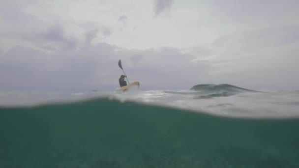 Plan fractionné d'une femme pagayant le kayak dans la mer calme avec vue sous-marine .