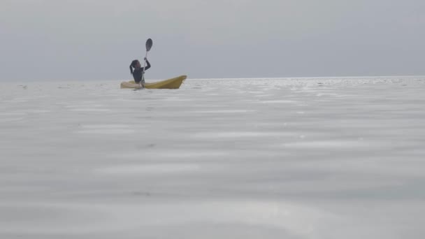 Młody turysta odkrywający i cieszący się przygodą kajakową w spokojnym oceanie. — Wideo stockowe