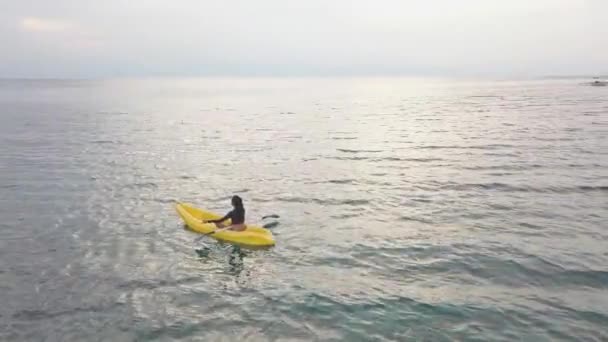 Mulher em um caiaque em uma posição lutos meditando no oceano pacífico. Vista para drones — Vídeo de Stock