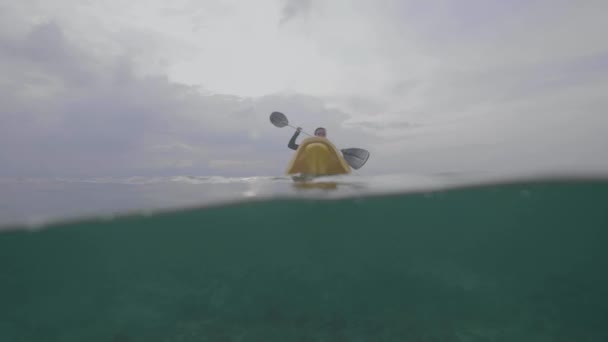 Plan divisé avec vue sous-marine. Jeune femme pagaie un kayak dans l'océan .