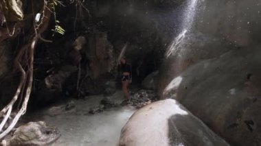 Yeraltındaki mağara şelalesinde tatlı su altında yürüyen bir kadın..