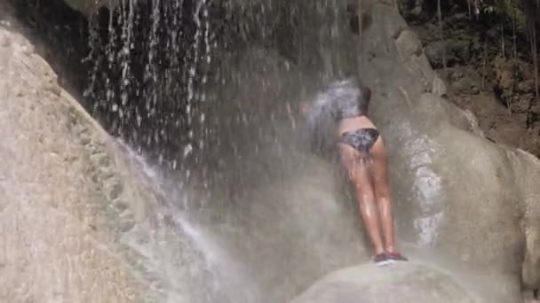 Mujer joven que se relaja bajo una cascada y disfruta bañándose. Concepto de vacaciones . — Vídeo de stock