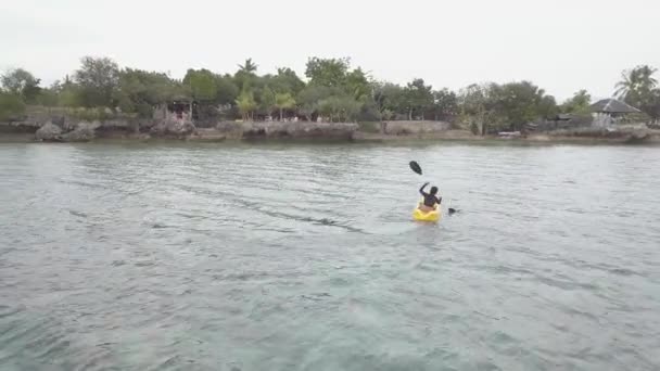 Drone footage: Een jonge vrouw kajakken in de oceaan in een tropisch resort. — Stockvideo