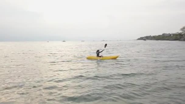 Aerial view of a young toursit enjoys kayaking in the peaceful ocean in summer. — Stock Video