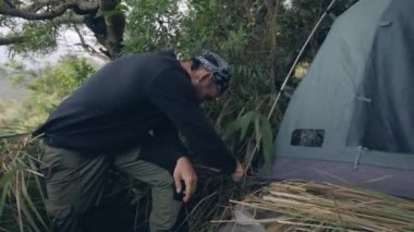 Man fixing tent, ready for camping in the mountain.