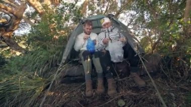 Güneş ve babam kampta kahvaltı yapıyor. Kaynamış yumurtaları plastik torbalarda soyuyorlar..