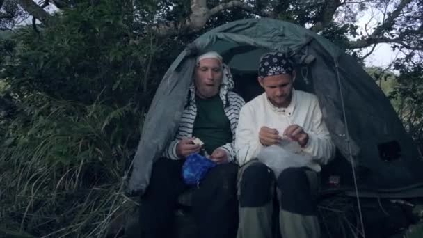 Resenärer män som äter middag sittande i tält i skogen camping på kvällen. — Stockvideo