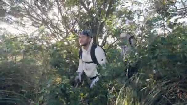 Deux hommes caucasiens marchant dans un champ herbeux allant à la montagne . — Video