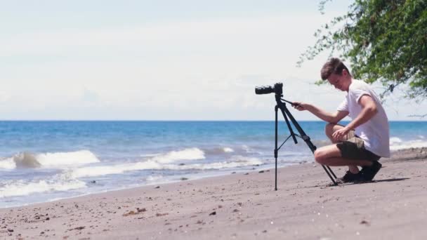 불균형 한 삼각대에 달린 DSLR 카메라가 모래 위로 떨어지다. — 비디오