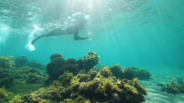 Underwater view of a woman against sunrays snorkeling in tuquoise ocean — Stock Video