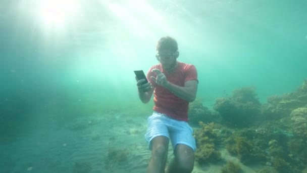 Pracujący człowiek na wakacjach odpowiada na telefony pod wodą. — Wideo stockowe