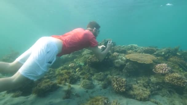 Un turista haciendo fotos y videos bajo el agua usando una cámara digital. Extraño. — Vídeo de stock