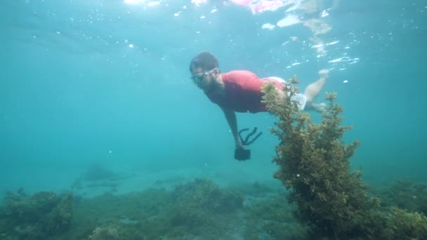 Een man die onder water zwemt terwijl hij een drone en een digitale camera vasthoudt. — Stockvideo