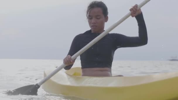 Close up shot of a young woman paddling on kayak boat in the ocean at sunny day — Stock Video