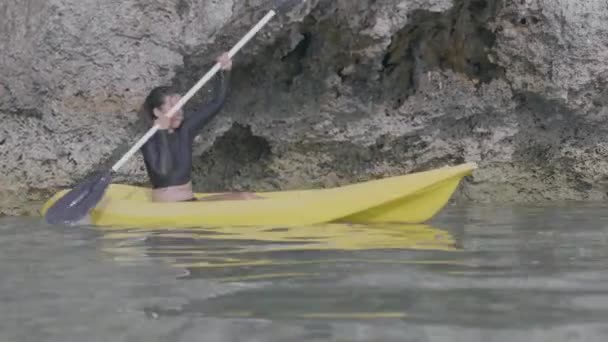 Joven mujer bonita remando un kayak de mar amarillo en un resort tropical .. — Vídeos de Stock
