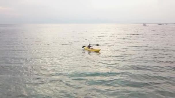 Vue aérienne : Une jeune femme kayak seule dans un océan tropical serein en été . — Video