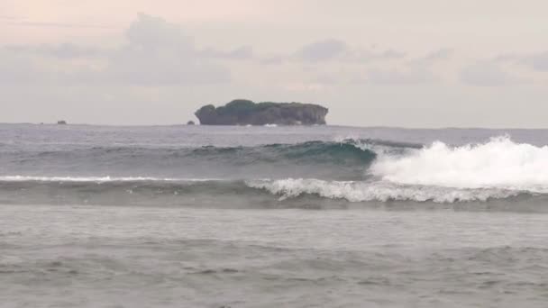 Seascape view of small rock island and breaking waves near seashore. — Stock Video