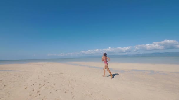 Chica asiática se ejecuta en la playa de arena cerca del océano en el día soleado en la isla tropical . — Vídeo de stock