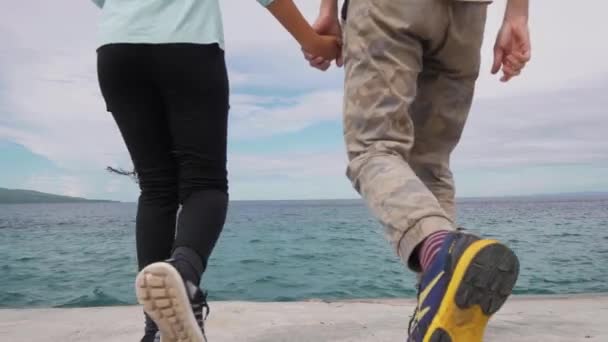 Slow motion: Young couple holds hands walking on the boulevard, close up shot. — Stock Video