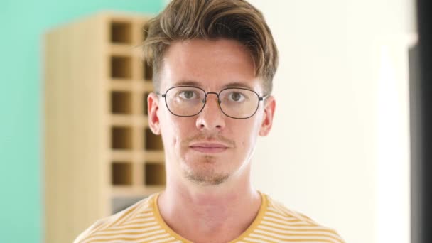 Retrato de un tipo de aspecto inteligente con gafas sonriendo a la cámara en casa . — Vídeos de Stock