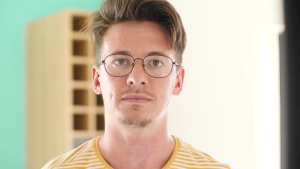 Портрет молодого розумного хлопця в окулярах, який посміхається в камеру . — стокове відео