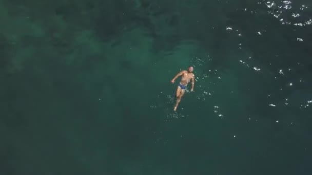 Ein fitter junger Mann schwimmt gern und schwimmt im Sommer im blauen Meer. — Stockvideo