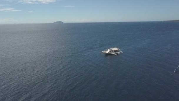 Вид с воздуха на маленькую туристическую лодку, причаливающую в голубом спокойном океане в летний день . — стоковое видео