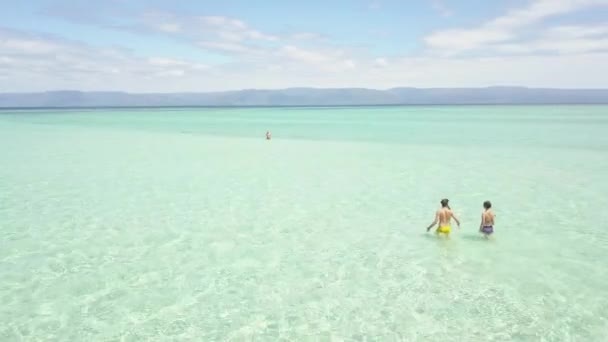 Vol aérien au-dessus de la plage paradisiaque avec touriste dans l'eau calme cristalline . — Video