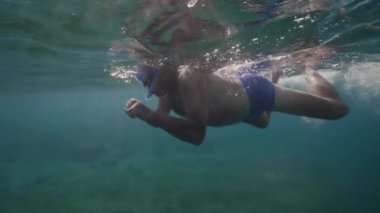 Güneşli bir günde açık okyanusta yüzen emekli yaşlı bir adamın sualtı görüntüsü..