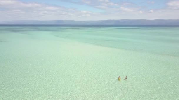 Vue aérienne du couple de touristes marchant dans l'eau cristalline de l'océan peu profond . — Video