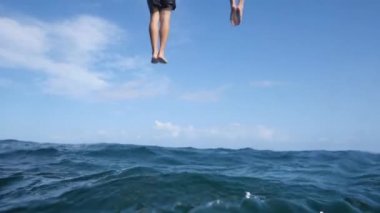 İki genç adamın arka görüntüsü yazın gökyüzü manzaralı mavi okyanusa düşer..