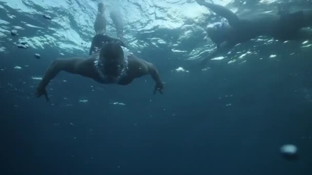 一个戴着面具的年轻人在阳光灿烂的蓝海下游泳. — 图库视频影像