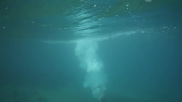 Un hombre salta y se sumerge desde un puente en el agua en el océano en el día de verano . — Vídeos de Stock