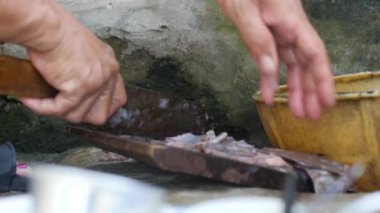 Kadınların eski bıçakla balık kestiği Asyalı kirli bir mutfak. Kapat..