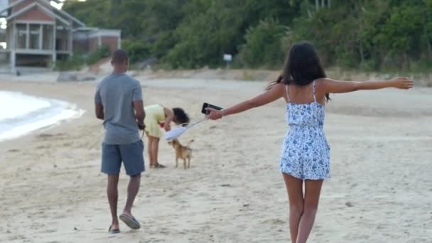 Zorgeloos aziatisch meisje in de zomer jurk verhogen handen en draaien rond op het strand. — Stockvideo