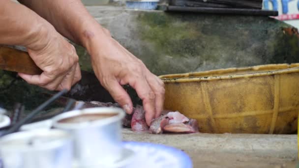 Mulheres velhas mão cortando peixe em uma tábua de madeira na cozinha suja asiática . — Vídeo de Stock